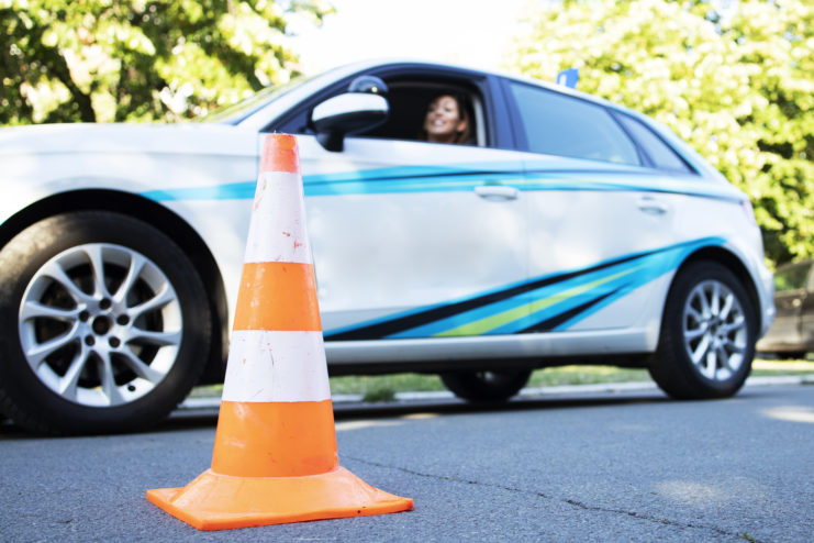 homem fazendo o exame de direção do detran na hora da baliza perto de cones de transito