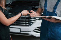 Pessoa segurando uma prancheta e passando a chave de um carro para outra pessoa