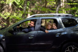 Família dentro de um SUV sorrindo pela janela do carro
