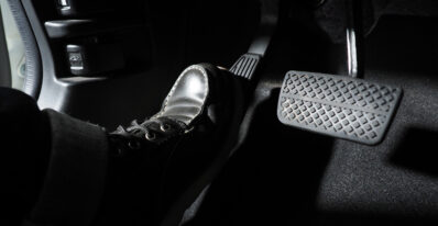Close do pé de uma pessoa no pedal do freio de um carro