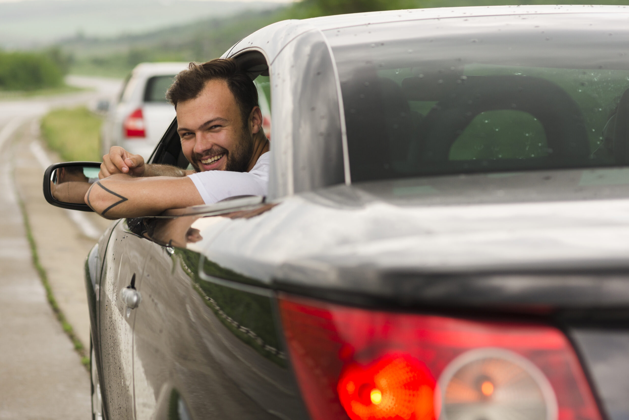 Homem branco feliz acenando para trás pela janela do seu carro